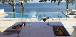 A table of food with an infinity pool overlooking the sea.