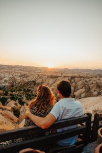 A couple gazing into the distance in a desert landscape at sunset.