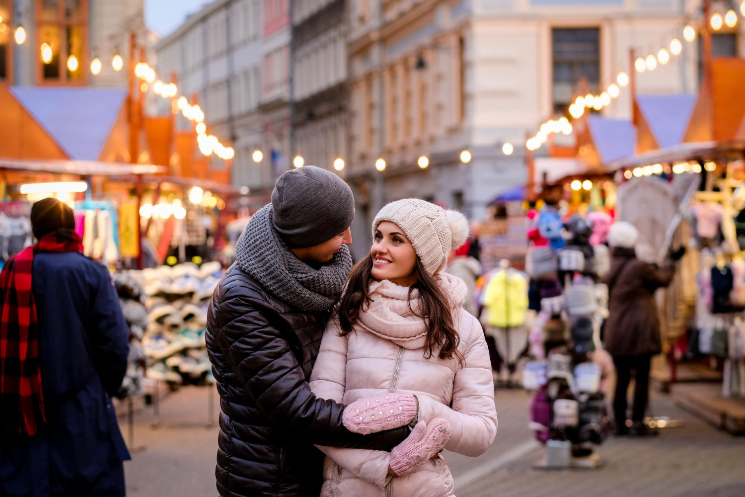 A couple embracing and looking at each other in a Christmas market.