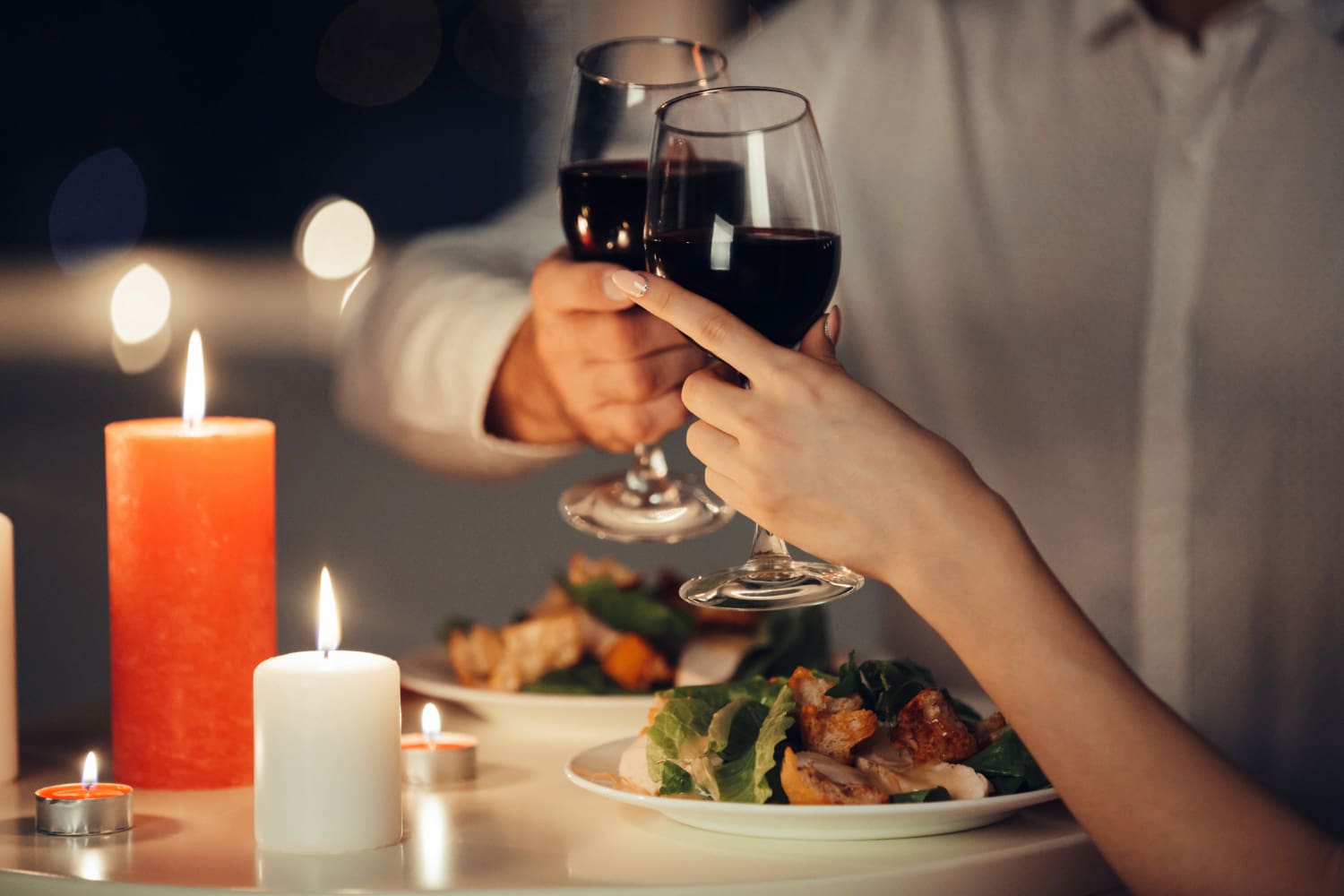 A couple toasting with wine glasses during a candlelit dinner.