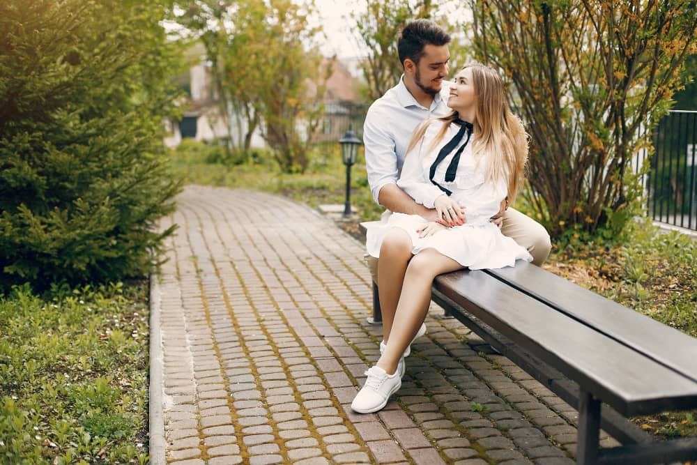 A couple lovingly holding each other on a park bench.
