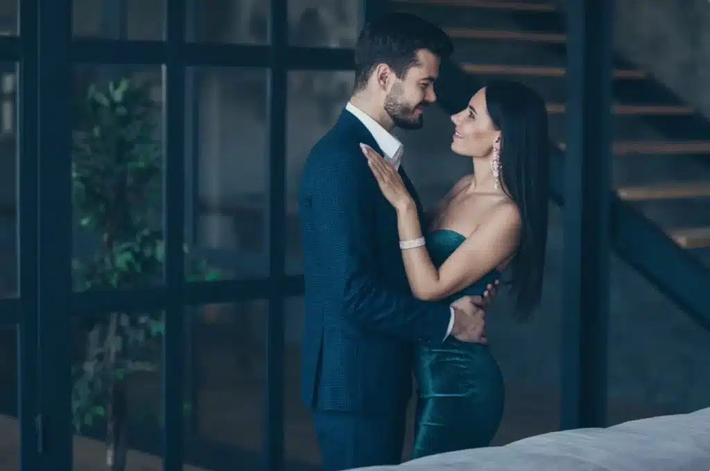 Close-up of a romantic couple in formal attire embracing and sharing a close look, emphasizing chemistry and emotional attraction in modern dating.